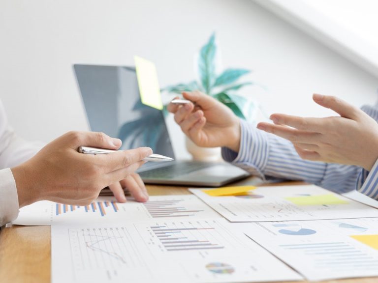 Two people discussing email list building charts and reports at a desk with a laptop in the background.