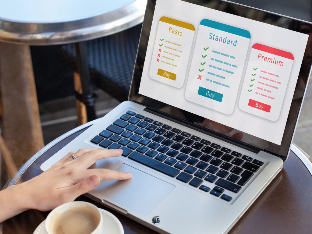 "Laptop screen displaying a pricing comparison chart with Basic, Standard, and Premium plans, featuring checkmarks and crosses to indicate included features, and 'Buy' buttons next to each plan."