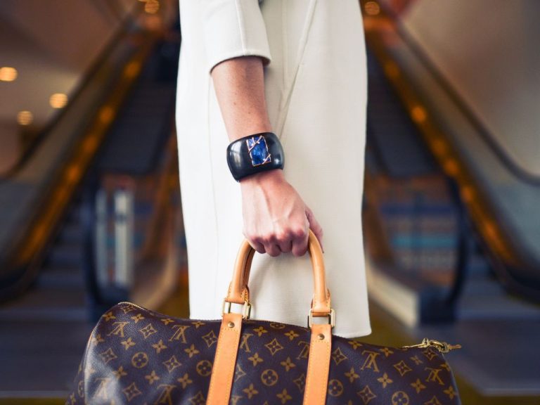 A person walking with a big watch and a handbag that looks expensive.