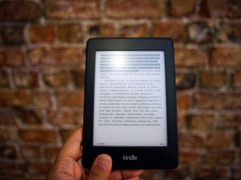 Kindle with e-book content held against a brick wall.