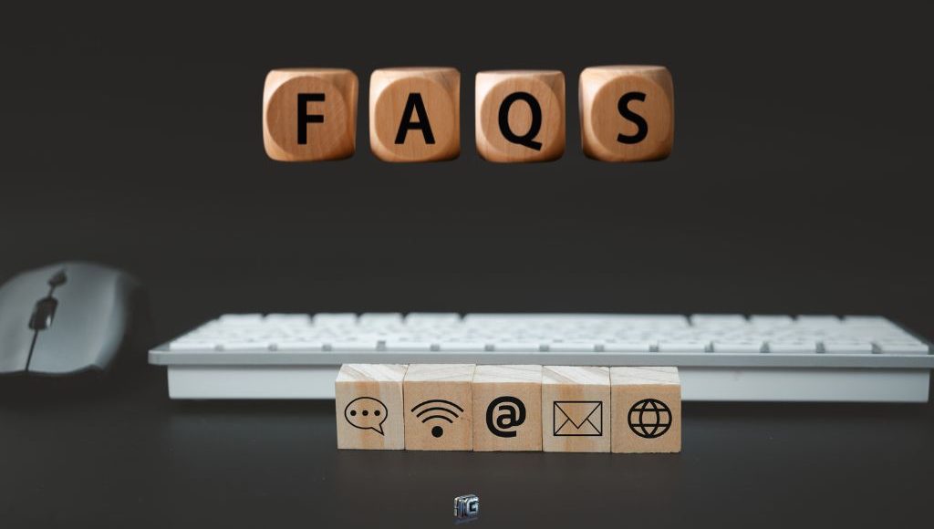 “Wooden blocks spelling ‘FAQs’ with communication icons and a keyboard and mouse in the background, symbolizing frequently asked questions about writing side hustles.”